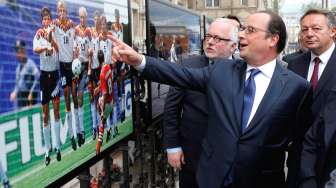 Presiden Prancis, Francois Hollande, bersama tokoh sepakbola Pierre Louis Basse, mengomentari salah satu foto Euro 1994 di sebuah pameran di Balai Kota Paris, Senin (9/5/2016). [Reuters/Francois Mori/pool]