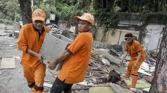 Pekerja Penanganan Sarana dan Prasarana Umum (PPSU) membersihkan lokasi pembongkaran tempat usaha tanaman hias di atas trotoar di kawasan Senayan, Jakarta, Minggu (22/5/2016). [Suara.com/Kurniawan Mas'ud]