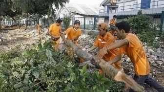 Pekerja PPSU DKI Jakarta membersihkan lokasi pembongkaran tempat usaha tanaman hias di atas trotoar di Jalan Asia-Afrika, Jakarta, Jumat (3/6/2016). [Suara.com/Kurniawan Mas'ud]