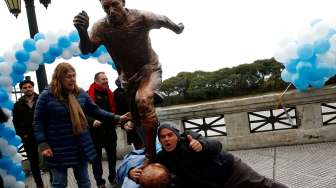 Seorang berfoto di bawah patung bintang Argentina Lionel Messi yang baru diresmikan di kota Buenos Aires. Reuters/Marcos Brindicci