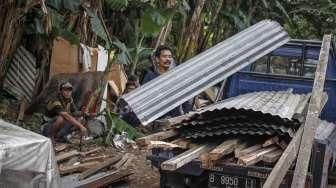 Petugas dibantu alat berat melakukan pembongkaran bangunan semi permanen yang berdiri di lahan milik PT Kereta Api Indonesia (KAI) di Kawasan Gunung Antang, Jatinegara, Jakarta, Senin (25/7/2016). [Suara.com/Kurniawan Mas'ud]