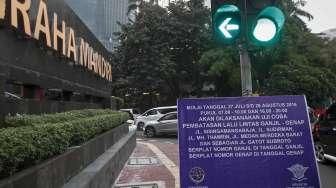 Petugas Polantas dan Dishub melakukan sosialisasi uji coba penerapan sistem pelat ganjil-genap melalui papan informasi, seperti terpampang di Jalan Imam Bonjol, Jakarta, Senin (25/7/2016). [Suara.com/Kurniawan Mas'ud]