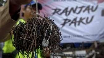 Relawan dari Komunitas Sapu Bersih (Saber) menunjukkan lebih dari 1.000 kilogram paku yang berhasil dikumpulkan dari sejumlah ruas jalan Ibu Kota, di Bundaran HI, Jakarta, Minggu (7/8/2016). [Suara.com/Kurniawan Mas'ud]