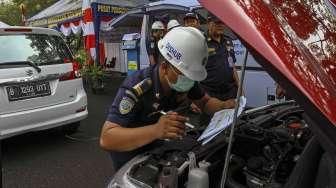 Petugas Dishub DKI Jakarta melakukan pemeriksaan uji KIR khusus kendaraan sewa berbasis transportasi online di kawasan Monas, Jakarta, Senin (15/8/2016). [Suara.com/Kurniawan Mas'ud]