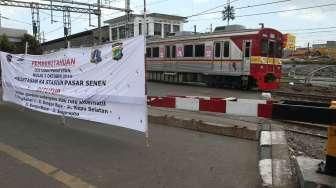 Pejalan kaki melewati pintu perlintasan kereta saat uji coba penutupan pintu perlintasan Kereta Api (KA) di Stasiun Pasar Senen, Jakarta, Sabtu (1/10). [Suara.com/Oke Atmaja]