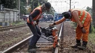 Sejumlah pekerja melakukan perawatan rel kereta api yang menghubungkan Jakarta-Bekasi di jalur Cipinang, Jakarta, Minggu (9/10/2016). [Suara.com/Kurniawan Mas'ud]