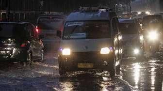 Sejumlah kendaraan tampak melintas di antara genangan banjir di kawasan Kalimalang, Jakarta, Minggu (9/10/2016). [Suara.com/Kurniawan Mas'ud]