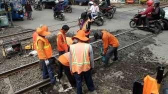 Sejumlah pekerja tampak tengah memperbaiki jalan yang berlubang di perlintasan kereta api kawasan Manggarai, Jakarta, Selasa (11/10/2016). [Suara.com/Oke Atmaja]