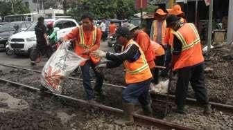 Sejumlah pekerja tampak tengah memperbaiki jalan yang berlubang di perlintasan kereta api kawasan Manggarai, Jakarta, Selasa (11/10/2016). [Suara.com/Oke Atmaja]