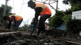 Sejumlah pekerja tampak tengah memperbaiki jalan yang berlubang di perlintasan kereta api kawasan Manggarai, Jakarta, Selasa (11/10/2016). [Suara.com/Oke Atmaja]