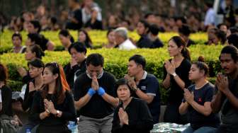 Khalayak tampak berdoa sementara iring-iringan kendaraan pembawa jenazah Raja Thailand, Bhumibol Adulyadej, melintas di dekat Istana Kerajaan di Bangkok, Jumat (14/10/2016). [Munir Uz Zaman/AFP]