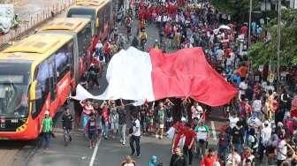 Peserta membentangkan bendera Merah Putih raksasa saat mengikuti Karnaval Cinta Budaya NKRI di kawasan Bunderan HI, Jakarta, Minggu (20/11/2016). [Suara.com/Oke Atmaja]