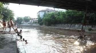 Sejumlah anak tampak asyik bermain air di kawasan Sungai Kenari, Jakarta, Minggu (20/11/2016). [Suara.com/Oke Atmaja]