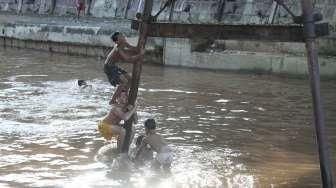 Sejumlah anak tampak asyik bermain air di kawasan Sungai Kenari, Jakarta, Minggu (20/11/2016). [Suara.com/Oke Atmaja]