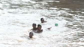 Sejumlah anak tampak asyik bermain air di kawasan Sungai Kenari, Jakarta, Minggu (20/11/2016). [Suara.com/Oke Atmaja]