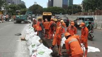 Petugas Pemeliharaan Prasarana dan Sarana Umum (PPSU) membuat jalur air di kawasan Jalan Jenderal Sudirman, Jakarta, Sabtu (3/12/2016). [Suara.com/Oke Atmaja]