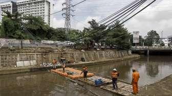 Petugas UPK Badan Air Taman Jalur Hijau Provinsi DKI Jakarta membersihkan sampah yang terbawa oleh aliran Kali Kwitang, di Jakarta, Kamis (12/1).