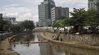 Petugas UPK Badan Air Taman Jalur Hijau Provinsi DKI Jakarta membersihkan sampah yang terbawa oleh aliran Kali Kwitang, di Jakarta, Kamis (12/1).