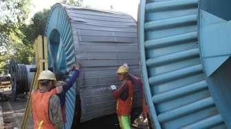 Pekerja menurunkan kabel bertegangan tinggi untuk dipasang di bawah tanah di kawasan Jalan Proklamasi, Jakarta, Jumat (19/1).