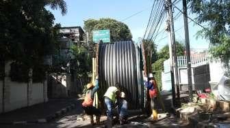 Pekerja menurunkan kabel bertegangan tinggi untuk dipasang di bawah tanah di kawasan Jalan Proklamasi, Jakarta, Jumat (19/1).