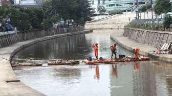 Petugas Pemelihara Prasarana dan Sarana Umum (PPSU) DKI atau yang sering disebut pasukan oranye, membersihkan sungai di kawasan Kwitang, Jakarta Pusat, Selasa (24/1).