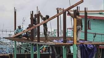 Pekerja tampak memperbaiki kapal pengangkap ikan yang berlabuh di dermaga Pelabuhan Ikan Muara Angke, Jakarta, Sabtu (28/1/2017). [Suara.com/Kurniawan Mas'ud]