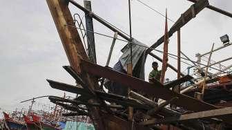 Pekerja tampak memperbaiki kapal pengangkap ikan yang berlabuh di dermaga Pelabuhan Ikan Muara Angke, Jakarta, Sabtu (28/1/2017). [Suara.com/Kurniawan Mas'ud]