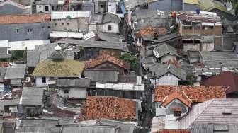 Deretan rumah penduduk dengan latar gedung apartemen dan perkantoran di Jakarta, Selasa (31/1).