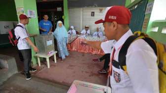 Petugas KPPS berkostum seragam pelajar sekolah dasar di TPS 45 Kelurahan Kebon Pala, Jakarta, Rabu (15/2).