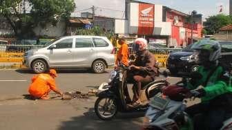 Petugas Penanganan Prasarana dan Sarana Umum (PPSU) menambal jalan berlubang di kawasan Kuningan, Jakarta, Jumat (17/2).