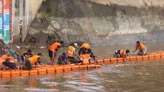 Petugas membersihkan sampah pada aliran Sungai Ciliwung yang menyumbat di Pintu Air Manggarai, Jakarta, Sabtu (18/2).