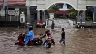 Warga melintasi banjir di kawasan Bendungan Hilir, Jakarta, Selasa (21/2).