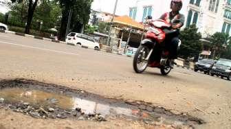 Sejumlah kendaraan tampak melintas di sela-sela jalan rusak di kawasan Sudirman, Sabtu (4/3/2017). [Suara.com/Oke Atmaja]