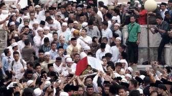 Prajurit TNI dan khalayak menggotong peti jenazah KH Hasyim Muzadi saat akan dimakamkan di Kompleks Pondok Pesantren Al Hikam, Beji, Depok, Jawa Barat, Kamis (16/3/2017). [Suara.com/Oke Atmaja]