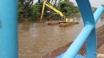 Menggunakan alat berat/ekskavator, petugas dari Dinas Tata Air DKI Jakarta mengeruk endapan lumpur bercampur sampah di Kali Pesanggrahan, Jakarta, Sabtu (1/4/2017). [Suara.com/Oke Atmaja]