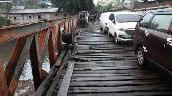 Warga melintasi jembatan yang rusak di Karet, Jakarta, Selasa (18/4).