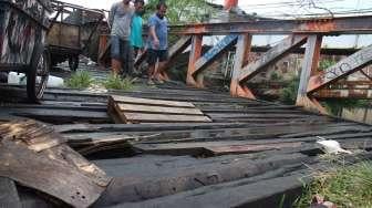 Warga melintasi jembatan yang rusak di Karet, Jakarta, Selasa (18/4).