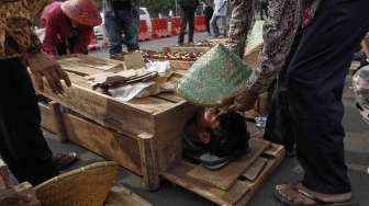 Puluhan anak usia 10-14 tahun warga Teluk Jambe melakukan aksi kubur diri di depan Istana Merdeka, Jakarta, Selasa (2/5).