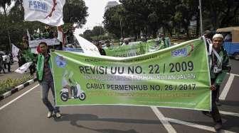 Pengemudi ojek online berunjuk rasa dengan berjalan kaki dari bundaran 'Patung Kuda' menuju Gedung Kementerian Perhubungan, Jakarta, Senin (15/5).