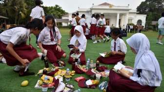 Sejumlah siswa SD membaca buku cerita yang dibagikan saat acara Gemar Baca dalam rangka Hari Buku Nasional, di halaman tengah Istana Merdeka, Jakarta, Rabu (17/5/2017). [Antara/Puspa Perwitasari]