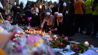 Masyarakat menyalakan lilin dan berdoa di kawasan Albert Square, Manchester, sebagai aksi solidaritas bagi korban aksi bom bunuh diri di Manchester Arena, Senin (22/5/2017) malam. (AFP)