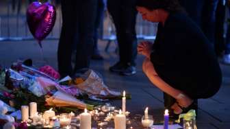 Masyarakat menyalakan lilin dan berdoa di kawasan Albert Square, Manchester, sebagai aksi solidaritas bagi korban aksi bom bunuh diri di Manchester Arena, Senin (22/5/2017) malam. (AFP)