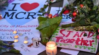 Masyarakat menyalakan lilin dan berdoa di kawasan Albert Square, Manchester, sebagai aksi solidaritas bagi korban aksi bom bunuh diri di Manchester Arena, Senin (22/5/2017) malam. (AFP)