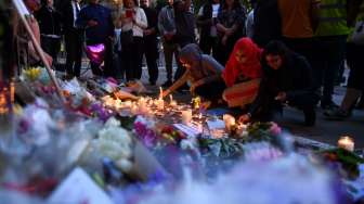 Masyarakat menyalakan lilin dan berdoa di kawasan Albert Square, Manchester, sebagai aksi solidaritas bagi korban aksi bom bunuh diri di Manchester Arena, Senin (22/5/2017) malam. (AFP)