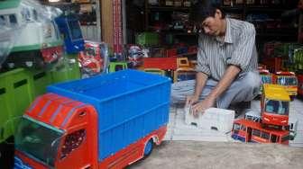 Pelaku Industri Kecil dan Menengah (IKM) menata dagangan berupa replika truk berbahan kayu di Jakarta, Rabu (21/6). [Suara.com/Oke Atmaja]