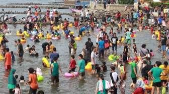 Pengunjung bermain di Pantai Ancol, Jakarta, Rabu (28/6). (Suara.com/Oke Atmaja)