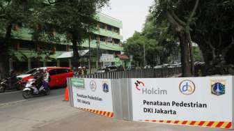 Pekerja menyelesaikan pembangunan pedestrian di Jalan Perwira, Jakarta, Selasa (18/7).