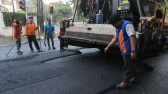 Sejumlah pekerja melakukan proses perbaikan jalan di kawasan Menteng, Jakarta, Senin (24/7).