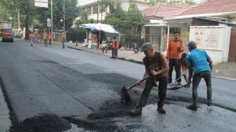 Sejumlah pekerja melakukan proses perbaikan jalan di kawasan Menteng, Jakarta, Senin (24/7).