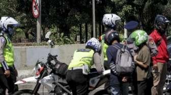 Petugas polisi terlihat melakukan penindakan kepada pengendara sepeda motor yang melanggar larangan melintas di jalan layang non tol Casablanca, Jakarta Selatan, Rabu (26/7/2017). [Suara.com/Kurniawan Mas'ud]